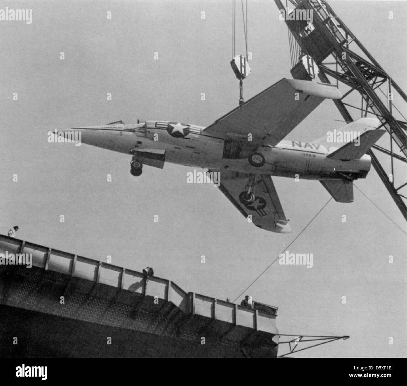 Un début de navy Grumman F11F-1 'tiger' d'être hissé à bord du USS forrestal (CVA-59) pour les essais de l'opérateur. Notez les ailes repliables vers le bas. Banque D'Images