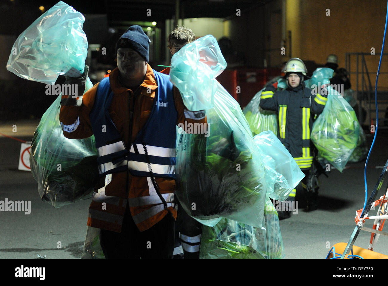 Les pompiers exécutent des sacs en plastique remplis de vêtements de protection contaminés à l'usine de Kraft Foods à Bad Fallingbostel, Allemagne, 16 octobre 2012. Alarme catastrophe a été déclenchée lorsqu'un réservoir de solution d'hydroxyde de sodium est par erreur rempli d'acide nitrique, produisant un nuage toxique de gaz nitreux considérés comme extrêmement dangereux s'ils entrent en contact avec la peau ou une Banque D'Images