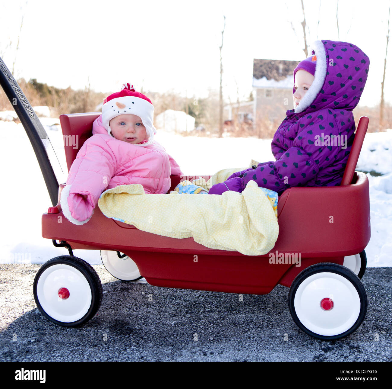 Fille avec petite Sœur assis dans Toy chariot Push Banque D'Images