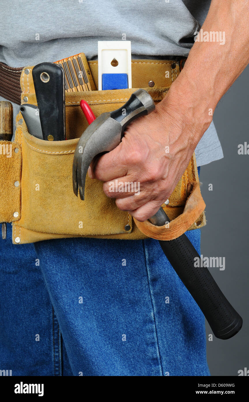 Libre d'un entrepreneur en tenant un marteau de sa ceinture d'outils, format horizontal, l'homme est méconnaissable. Banque D'Images