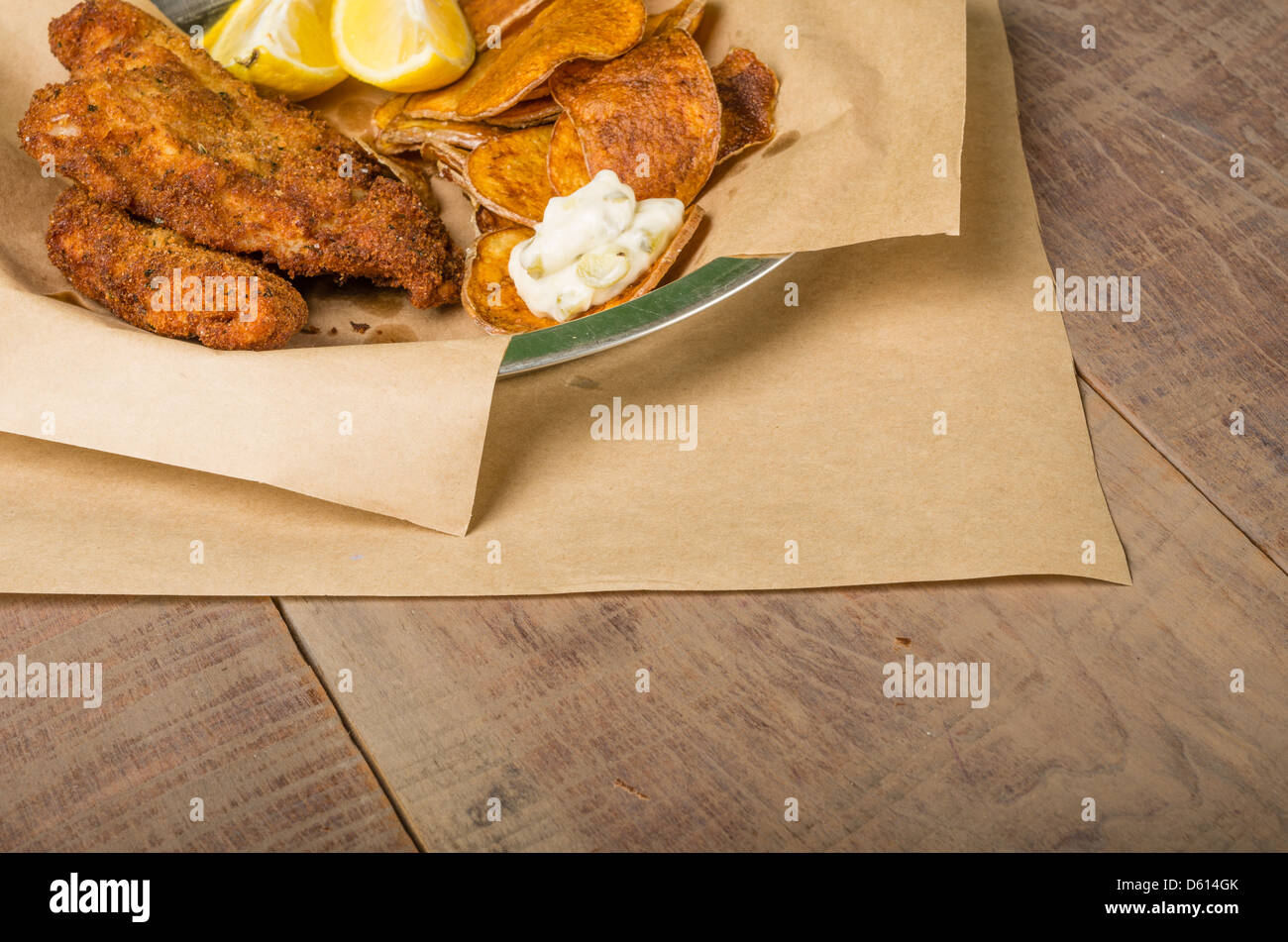 Le poisson frit et frites avec du citron sur une table en bois Banque D'Images