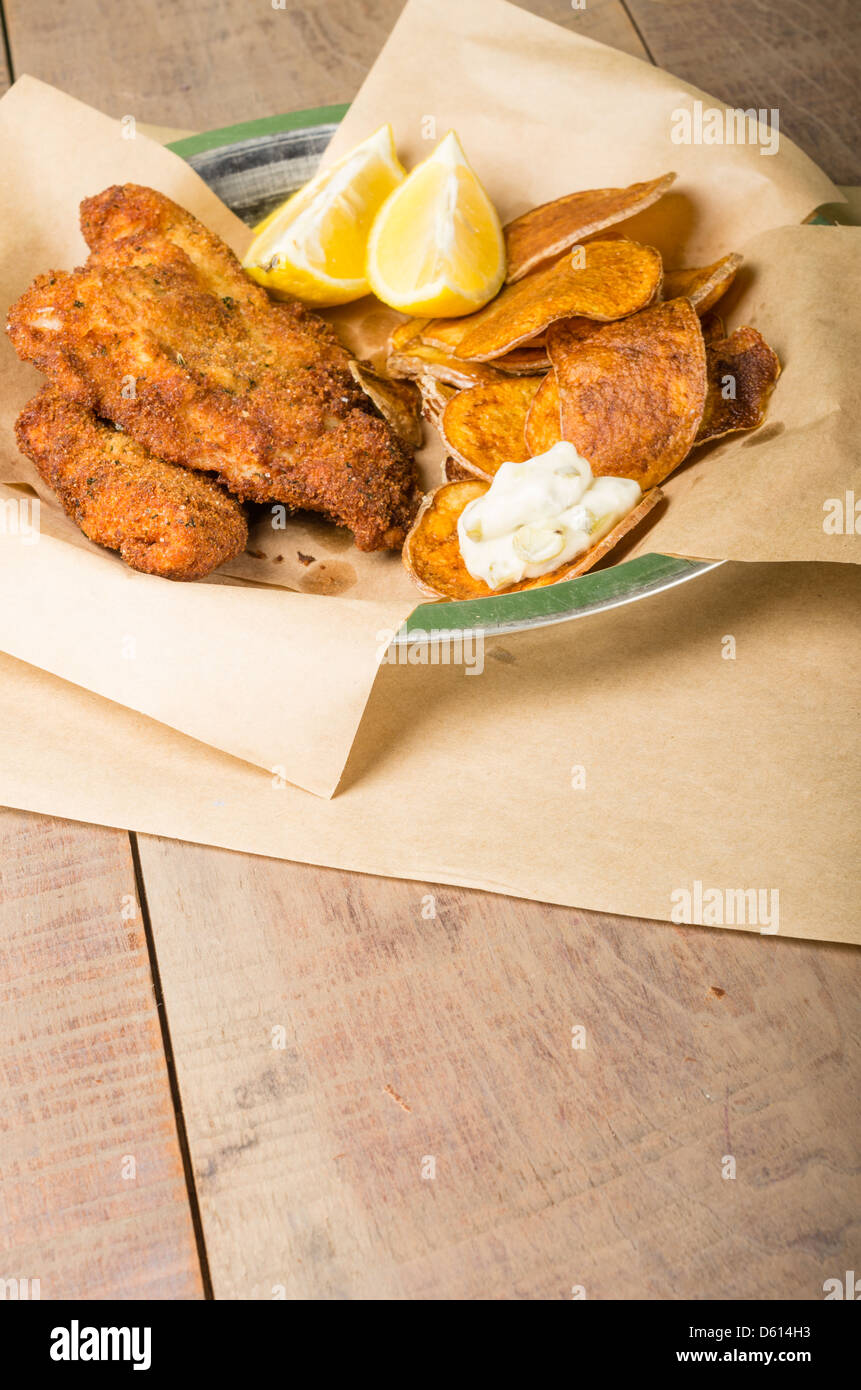 Le poisson frit et frites avec du citron sur une table en bois Banque D'Images