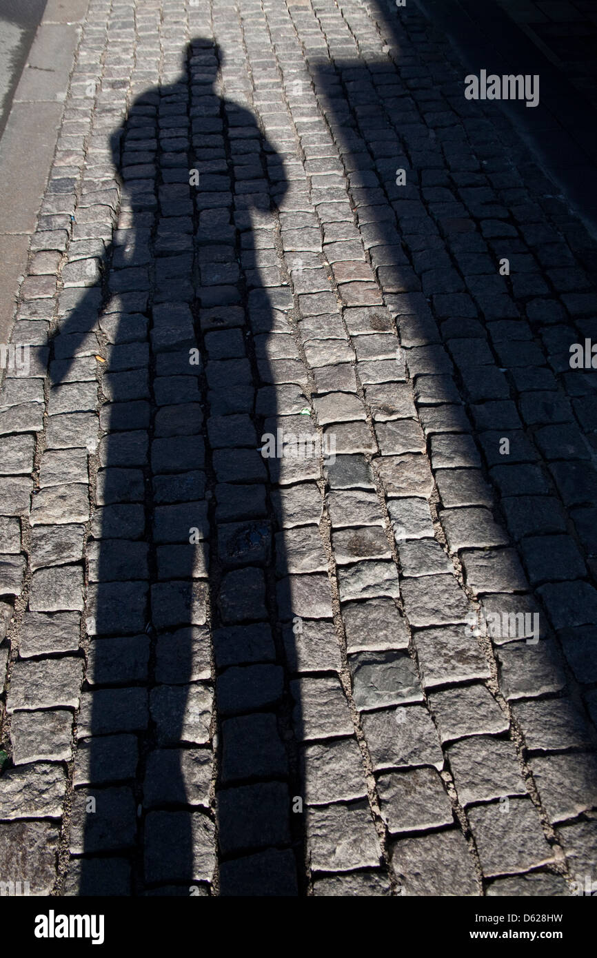 Grande ombre du photographe américain Dave Bartruff sur trottoirs pavés de Leipzig, Allemagne. Banque D'Images
