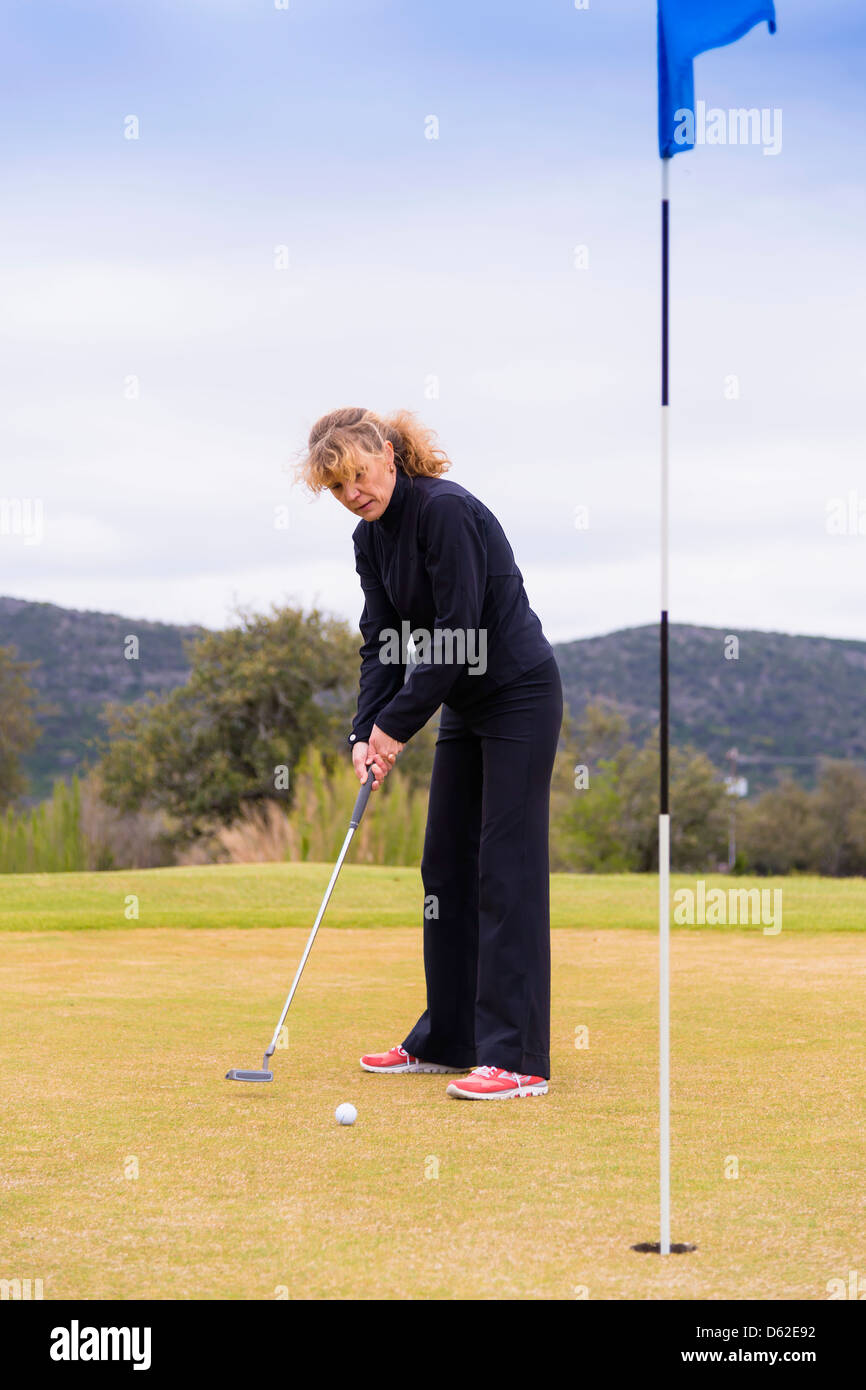 Femme de race blanche d'âge moyen de 45 ans en utilisant le putter sur un vert de golf Banque D'Images