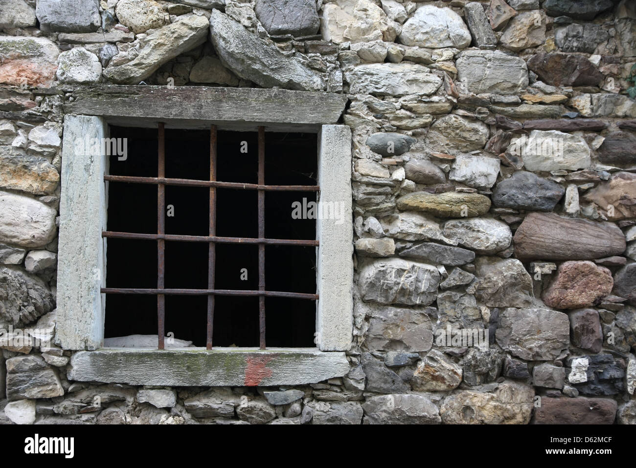 Fenêtre avec une grille métallique sur une ancienne grange en pierre Banque D'Images