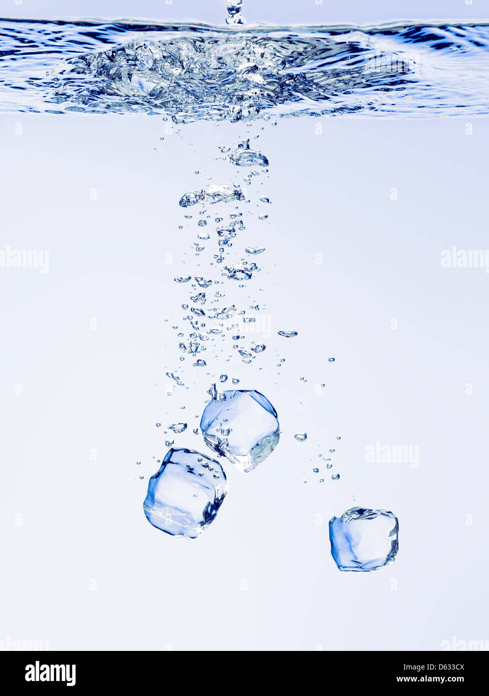 Des cubes de glace tombant dans l'eau claire, avec des bulles Banque D'Images