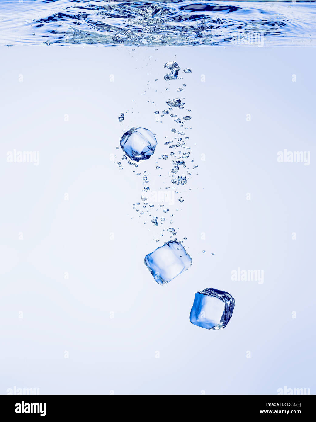 Des cubes de glace tombant dans l'eau claire, avec des bulles Banque D'Images