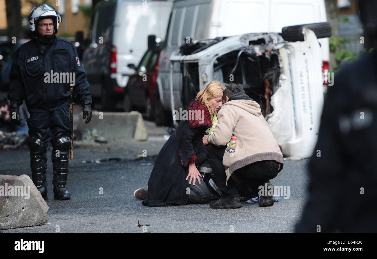 Les agents de police clairement le domaine de barricades, tandis que deux femmes prennent soin d'un homme blessé, qui a protesté contre un rassemblement néo-nazi avec la devise 'Journée de l'avenir" allemand à Hambourg, Allemagne, 02 juin 2012. Plusieurs milliers de personnes ont manifesté contre la marche de l'extrême droite. Photo : Christian Charisius Banque D'Images