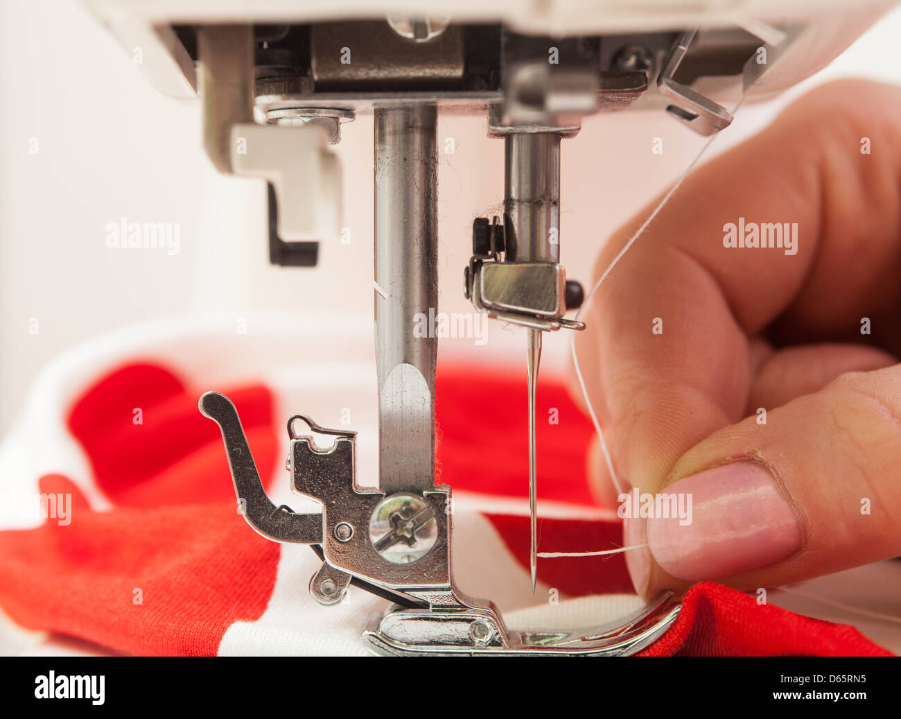 Un égout enfiler une aiguille dans la machine à coudre. Banque D'Images