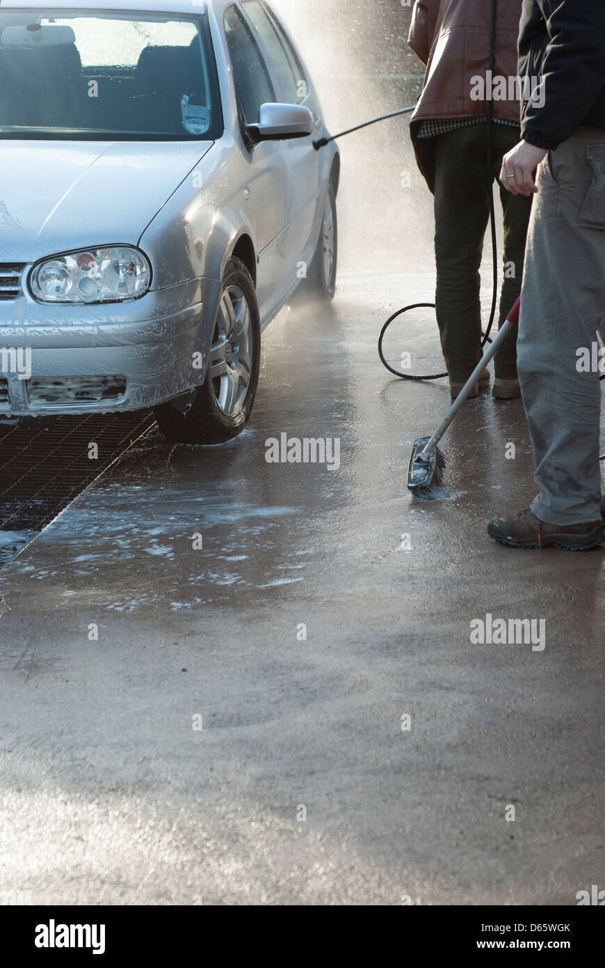 Un homme mûr et un jeune homme lave l'argent à un lavage de voiture Banque D'Images