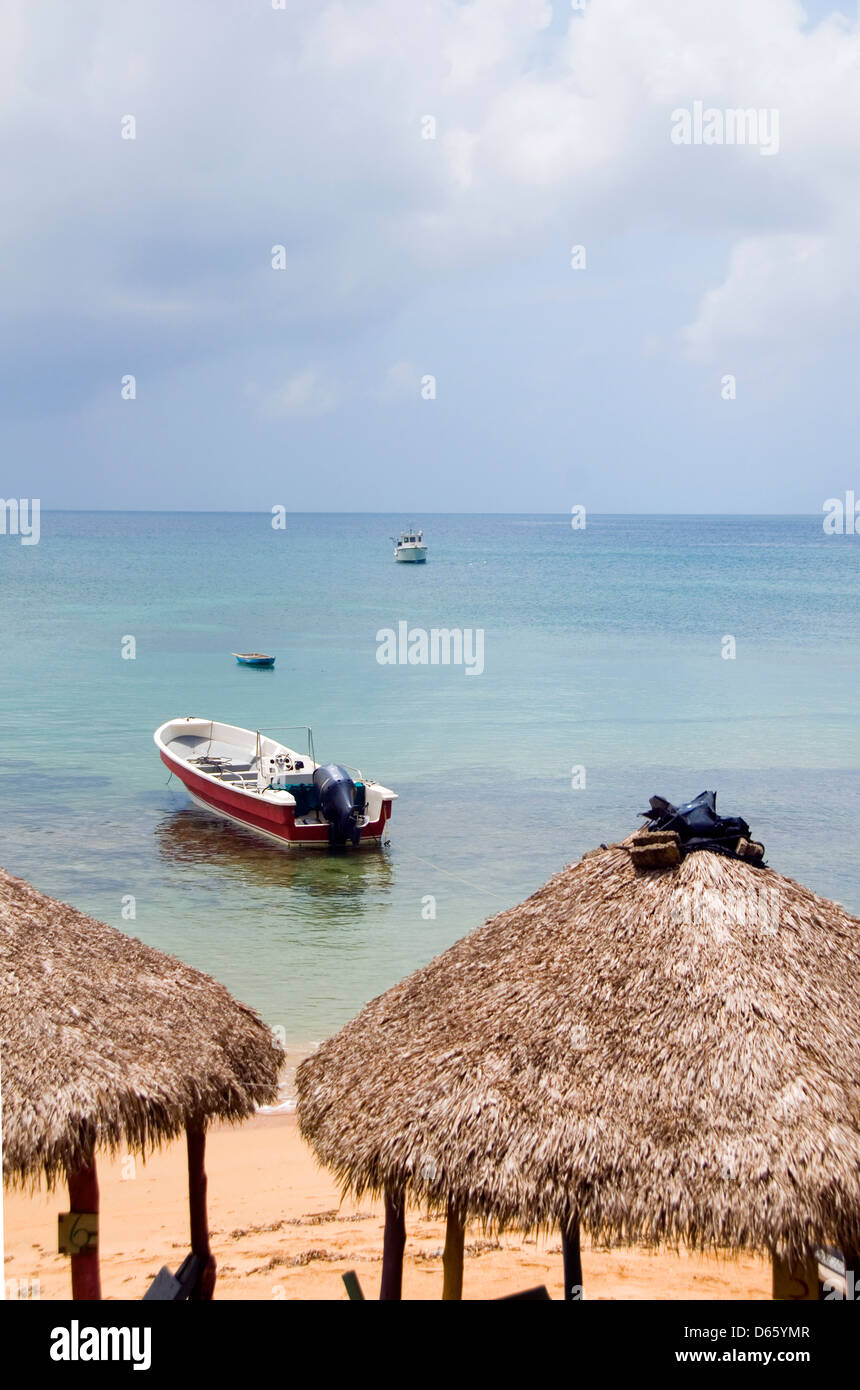 Toit de chaume plage restaurant huttes avec bateau de pêche dans la mer des Caraïbes sur l'île peu de maïs en Amérique centrale Nicaragua Banque D'Images