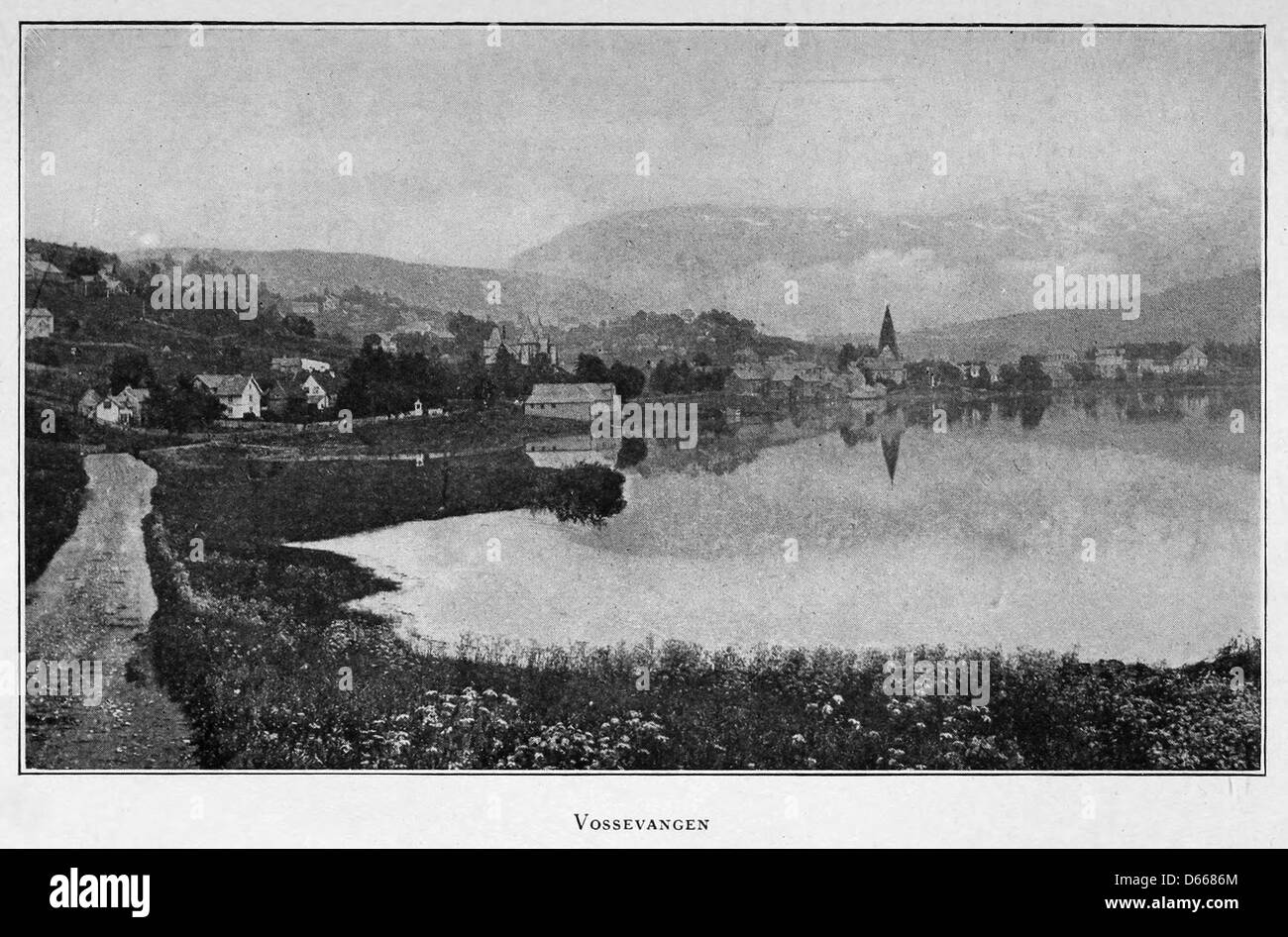 Cette photographie de 1922 capture Vossvangen, un village pittoresque en Norvège, présenté dans le journal «Un été dans les terres du Nord» L'image met en valeur la beauté naturelle de la campagne norvégienne, entourée de montagnes et de lacs. Banque D'Images