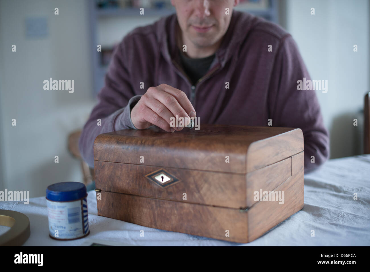 Homme d'âge moyen à une table de cuisine restaure une antique Victorian pente écrit prêt à vendre à une vente aux enchères ou antique shop Banque D'Images