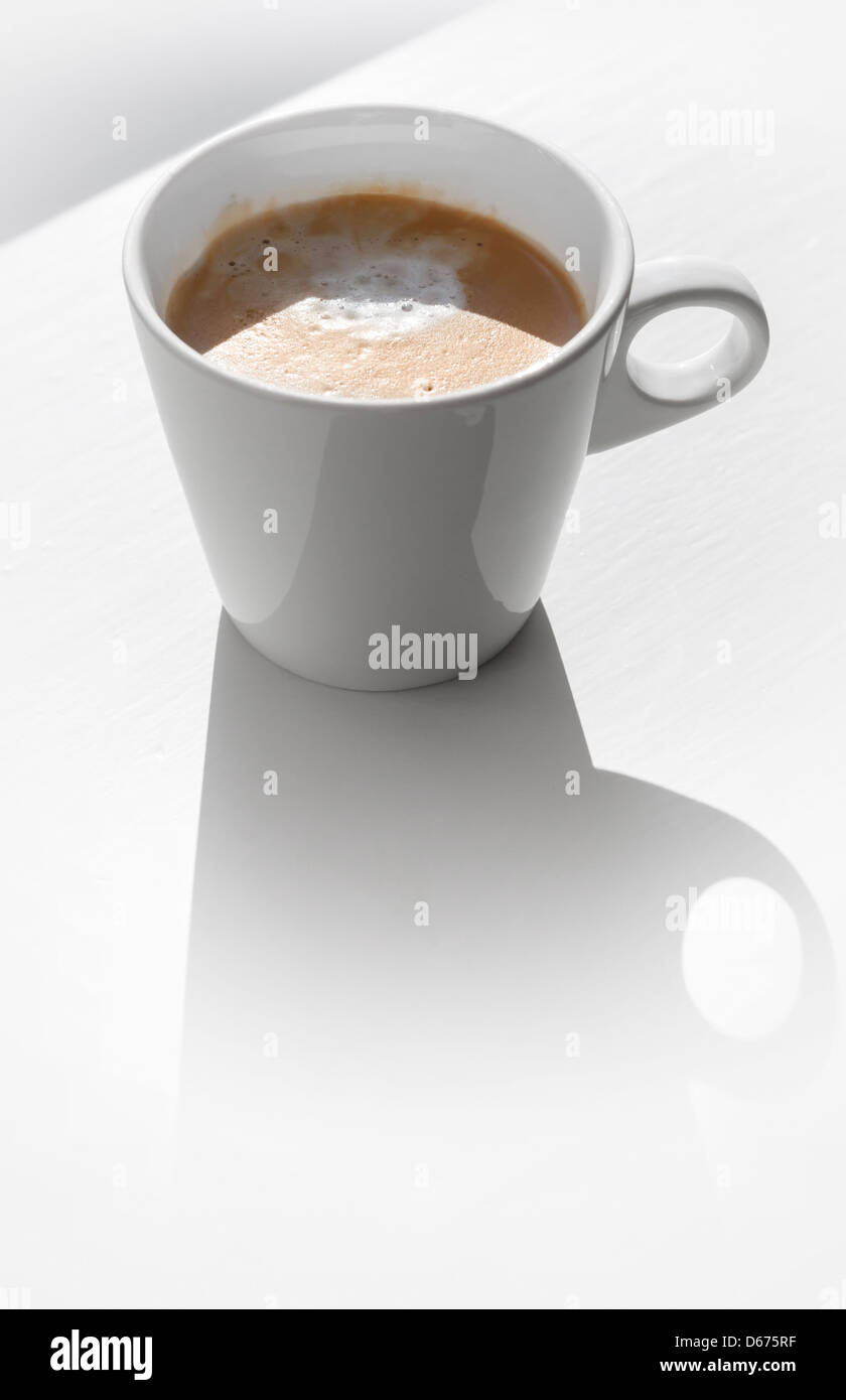 Cappuccino dans une tasse en céramique sur le tableau blanc avec ombre Banque D'Images