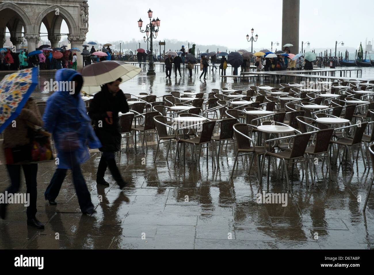 Les visiteurs s'abriter sous les parapluies à mesure qu'ils traversent un cours d'eau identifié la place Saint Marc, Venise, Italie Banque D'Images