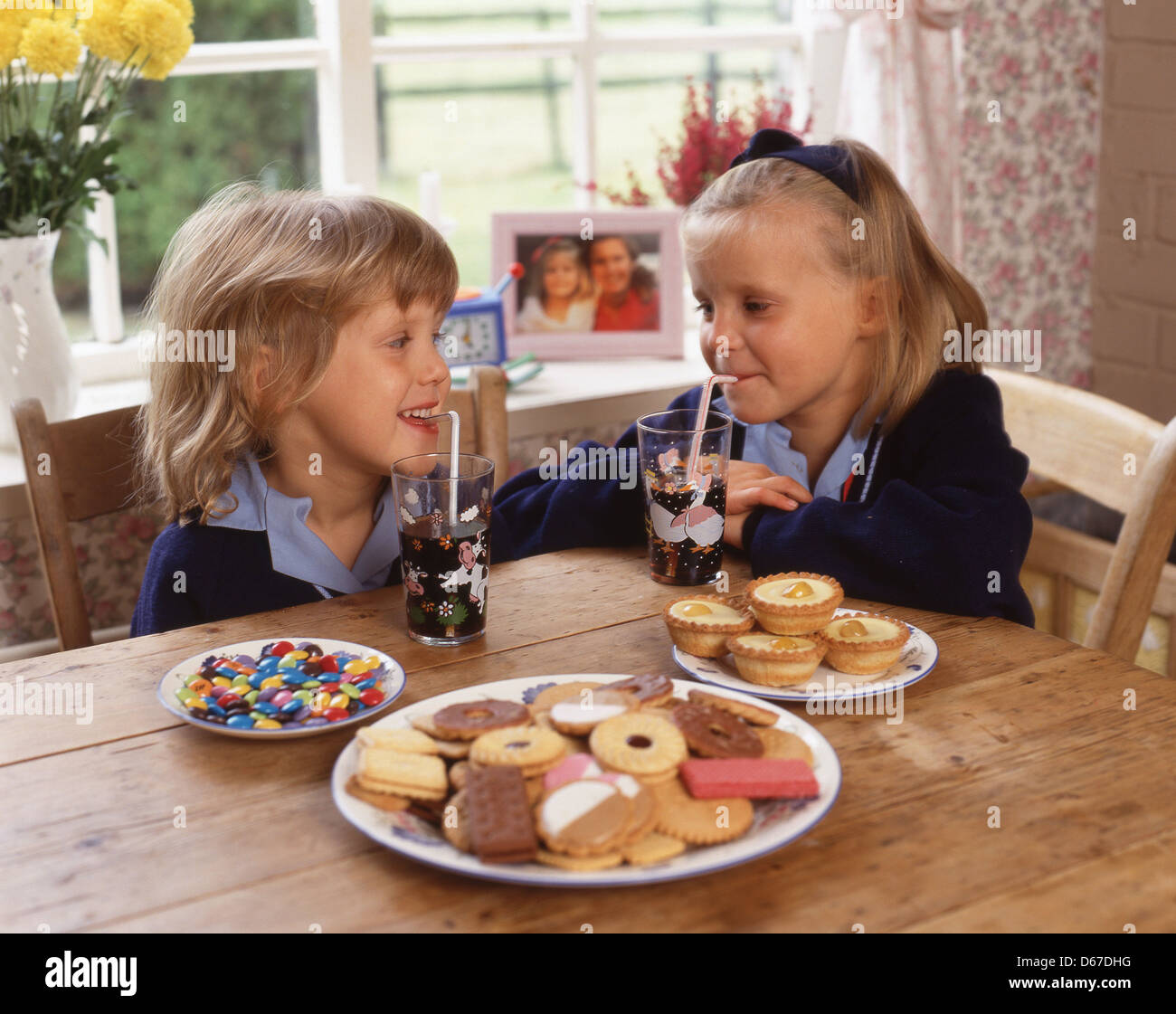Les jeunes filles avec des boissons, gâteaux, bonbons et biscuits (aliments malsains), Sunninghill, Berkshire, Angleterre, Royaume-Uni Banque D'Images