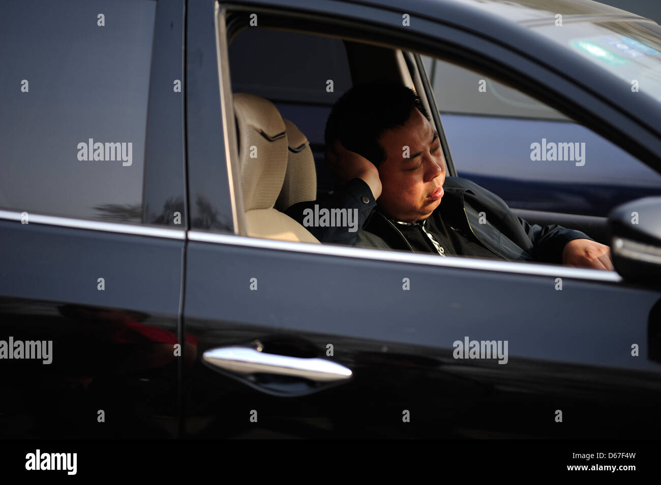 BEIJING, CHINE - avril 3:un homme ayant courte sieste dans sa voiture avant de durs retour à l'accueil de travailler à Beijing, Chine, le 3 avril 2013. Banque D'Images