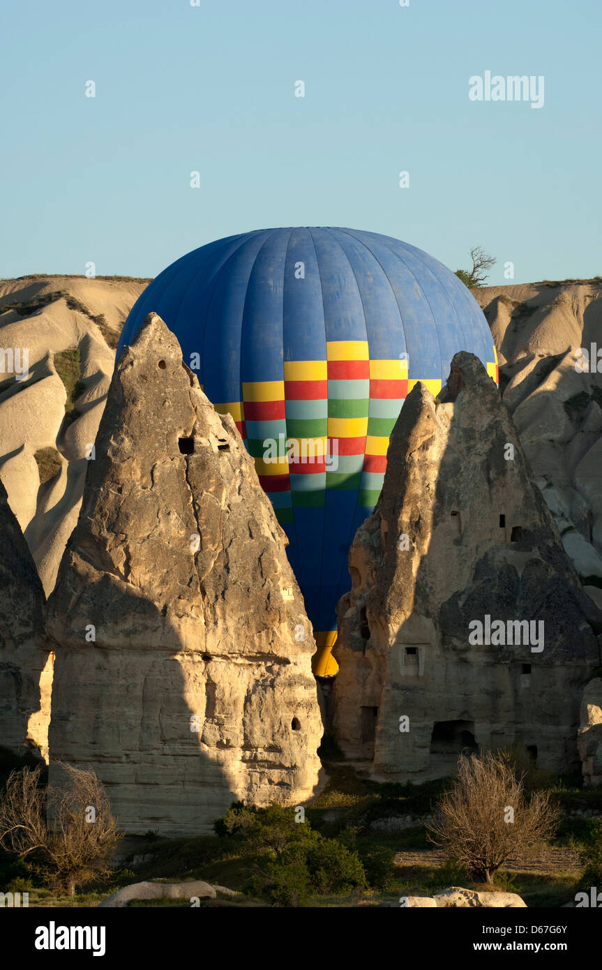 Hot Air Balloon manœuvres entre la roche de tuf cônes dans les sites de roche de la Cappadoce, Göreme, Turquie Banque D'Images