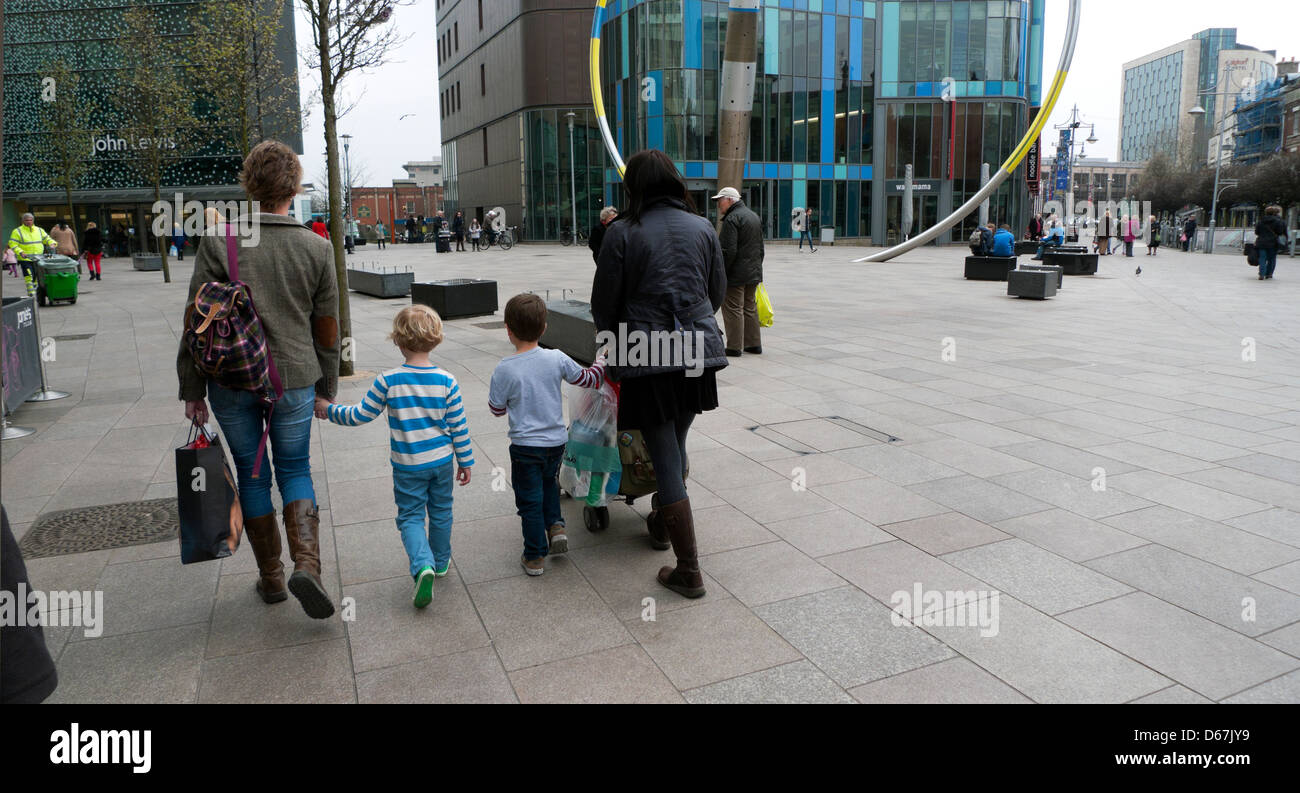 Vue arrière de la marche des mères avec des enfants dans la zone commerciale à l'extérieur de la bibliothèque de Cardiff & John Lewis department store à Cardiff au Pays de Galles KATHY DEWITT Banque D'Images