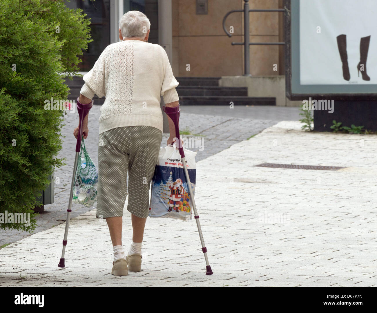 Une femme âgée s'approche d'une publicité montrant une paire de bottes noires à Suhl, Allemagne, 19 juin 2012. Photo : Soeren Stache Banque D'Images