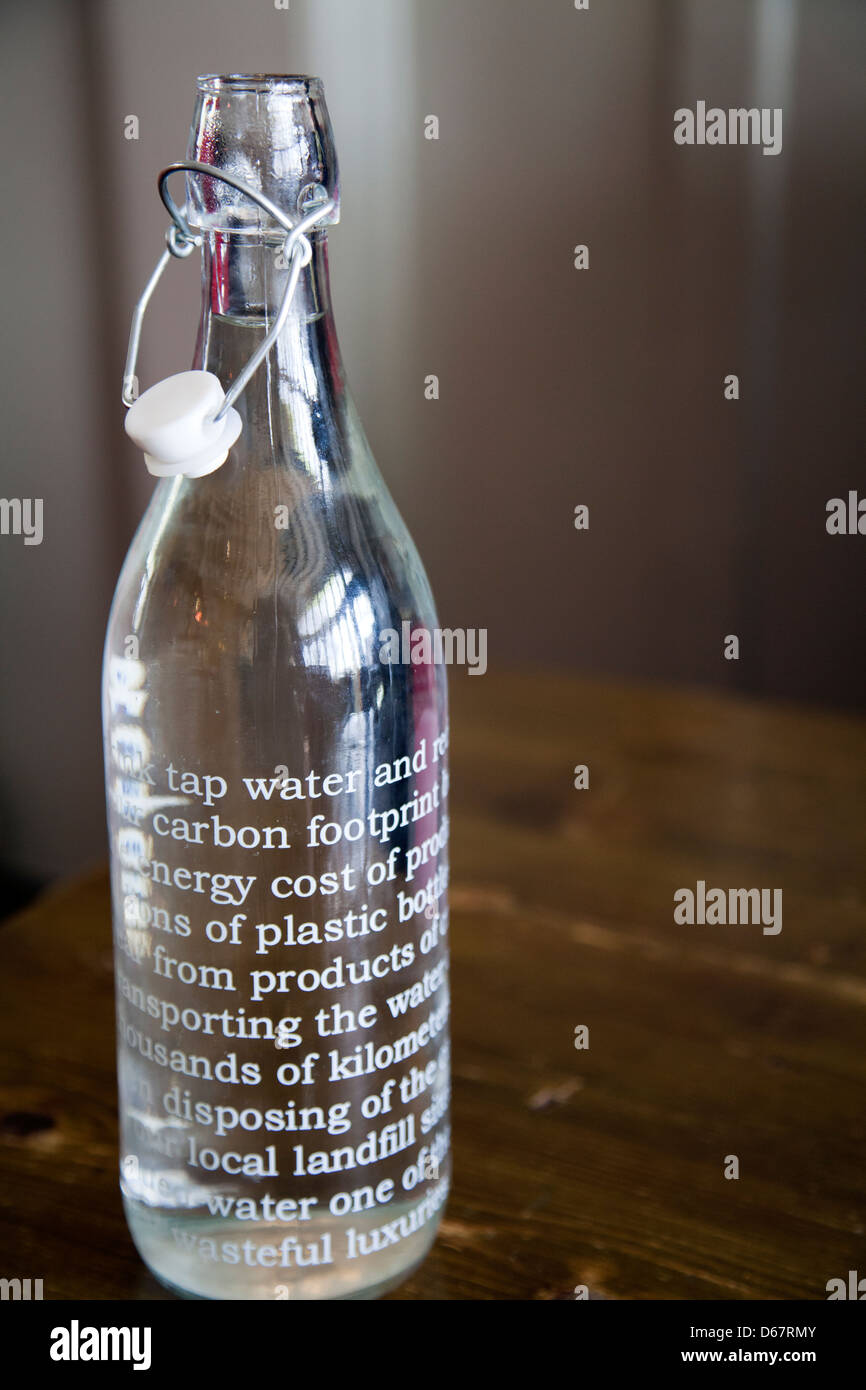 Bouteille de l'eau du robinet avec un message en faveur de l'empreinte carbone du verre au lieu de plastique - UK Banque D'Images