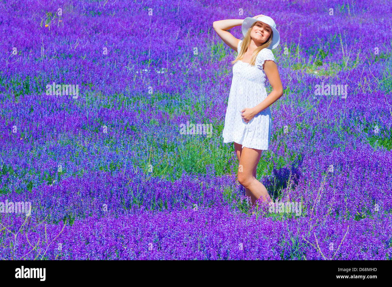 Jolie fille bronzage dans la clairière de lavande, bénéficiant de la lumière du soleil brillant et violet fleurs paysage, s'amuser en plein air en été Banque D'Images