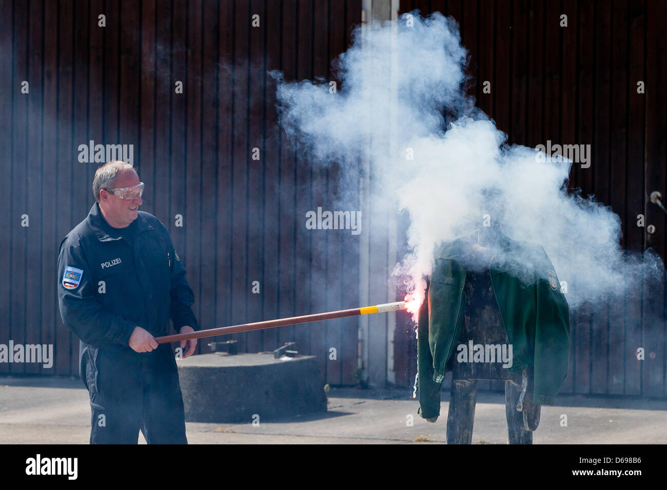 Un expert de l'enlèvement des explosifs définit une veste en feu avec une poussée dans les locaux de la police à Nuremberg, Allemagne, 02 août 2012. Des agents de la police criminelle de l'État de Bavière a démontré le danger de la pyrotechnie à les stades de football. Photo : Daniel Karmann Banque D'Images