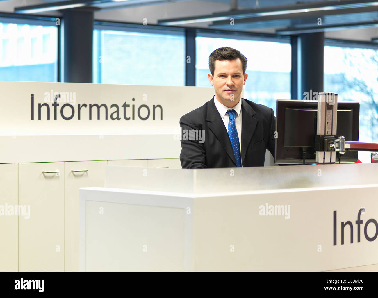 Réceptionniste smiling at information desk Banque D'Images