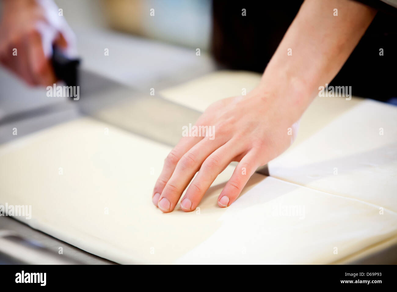 Baker slicing dough in kitchen Banque D'Images