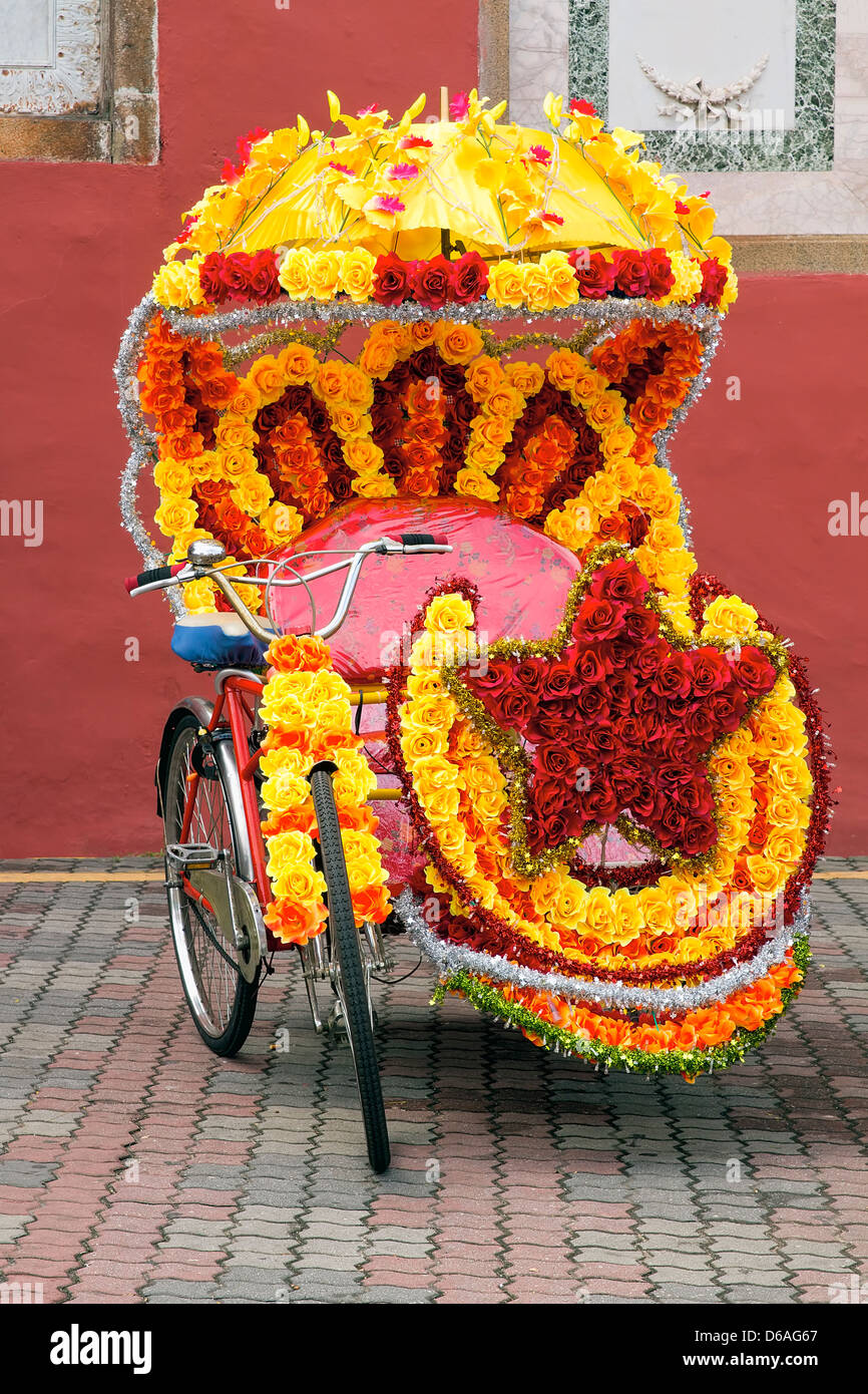 L'une des nombreuses attractions touristiques de Rickshaws Tricycle décorées avec des fleurs en soie colorés dans Melaka en Malaisie Banque D'Images