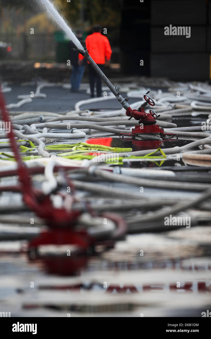 Les flexibles de saupoudrer d'un hall d'une usine de mousse où un gaz toxique accident causé opération d'envergure à Oestrich-Winkel, Allemagne, 14 août 2012. Pour éviter l'évasion de la substance contenant de l'acide cyanhydrique le réservoir avait été refroidi avec de l'eau. Photo : Fredrik von Erichsen Banque D'Images