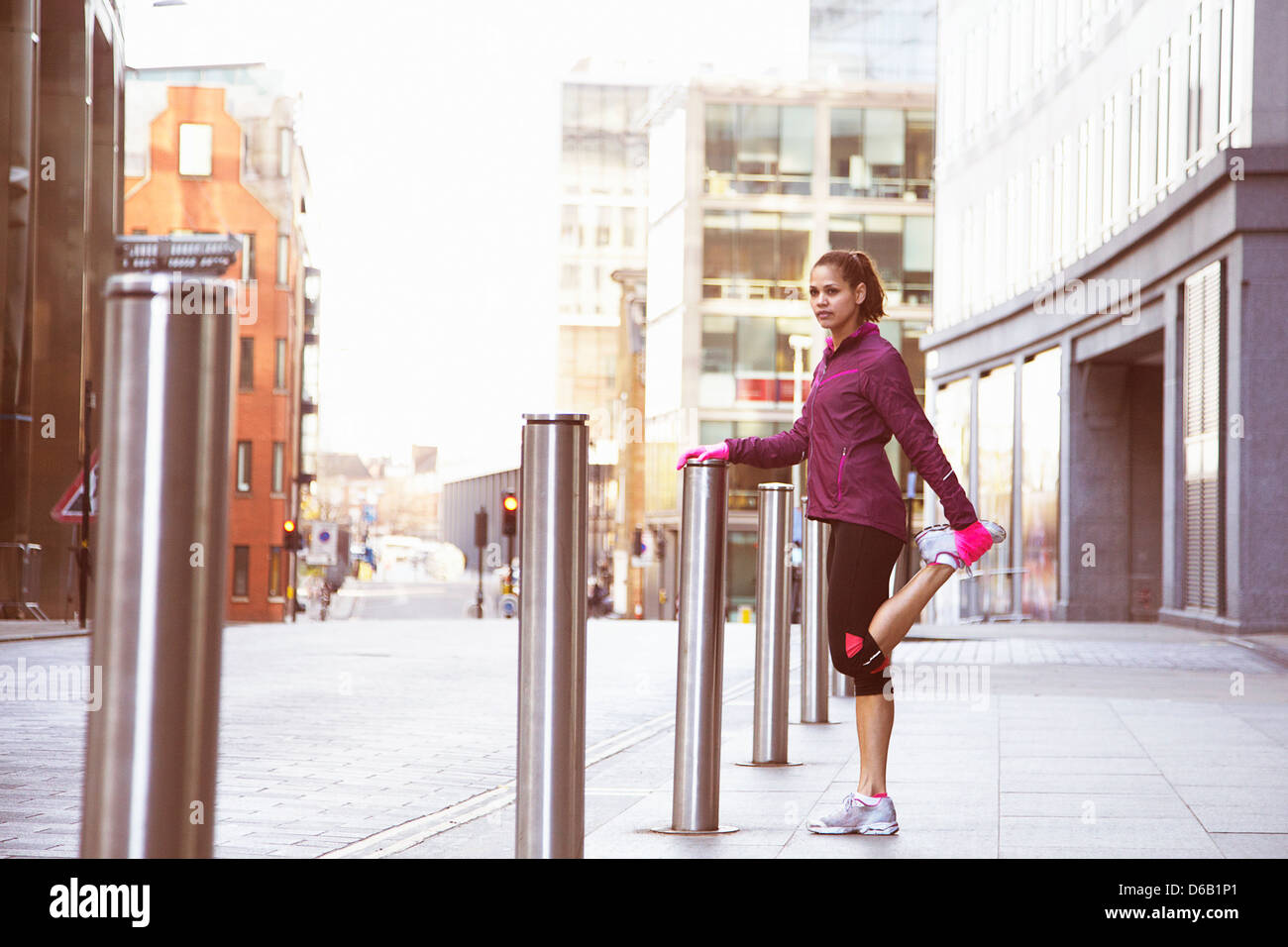 Woman stretching on city street Banque D'Images