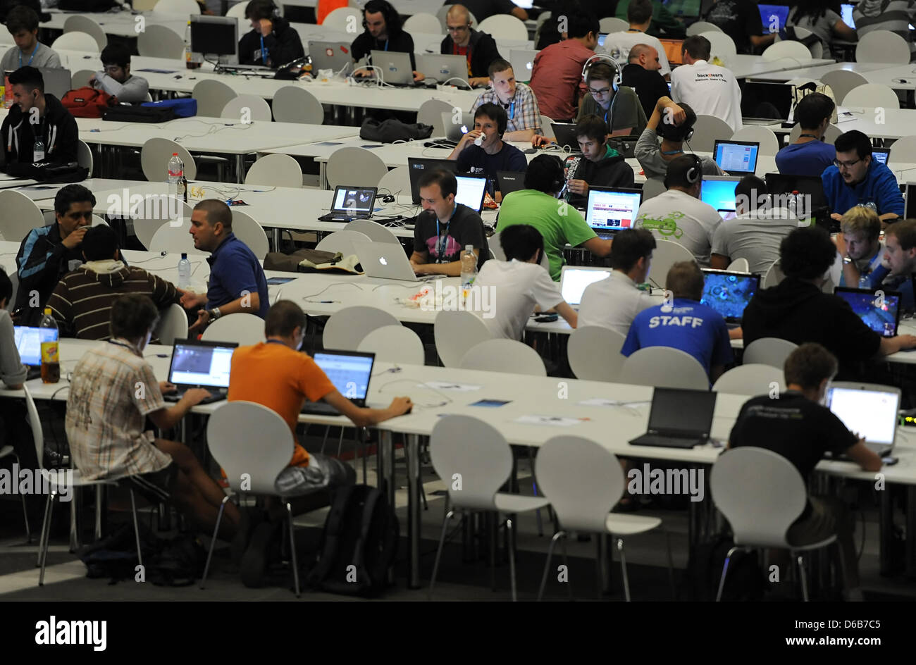 Les visiteurs de la Campus Party Europe, une réunion de jeunes blogueurs et programmeurs, assis à un bureau à l'ancien aéroport de Tempelhof à Berlin, Allemagne, 21 août 2012. Plusieurs milliers de jeunes inventeurs, des blogueurs et des programmateurs de 66 pays ont participé à la réunion de six jours au cours de laquelle ils ont discuté de la technologie, de la recherche, de l'économie et la politique. Photo : BRITTA PEDERSEN Banque D'Images