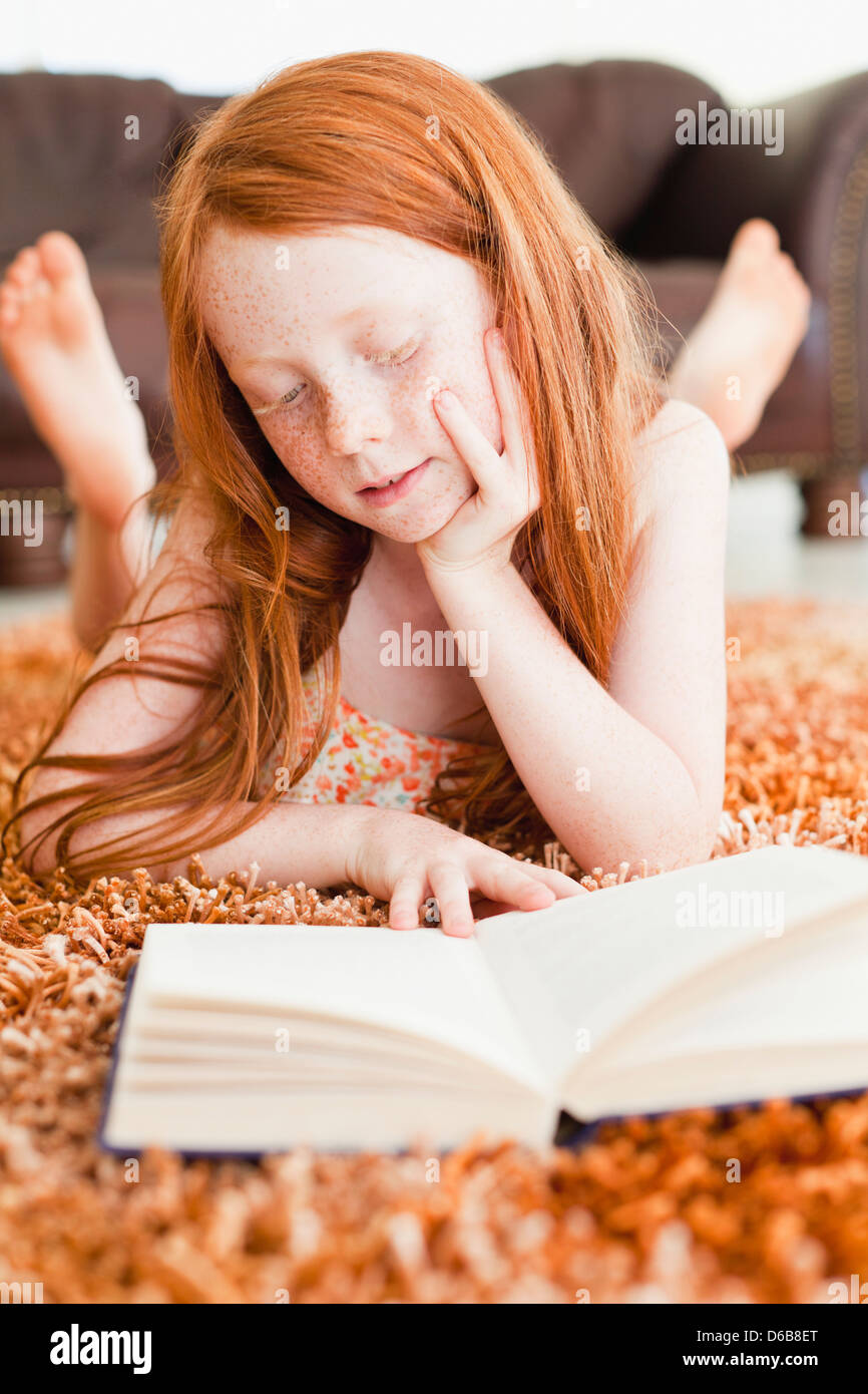 Girl reading sur plancher du salon Banque D'Images
