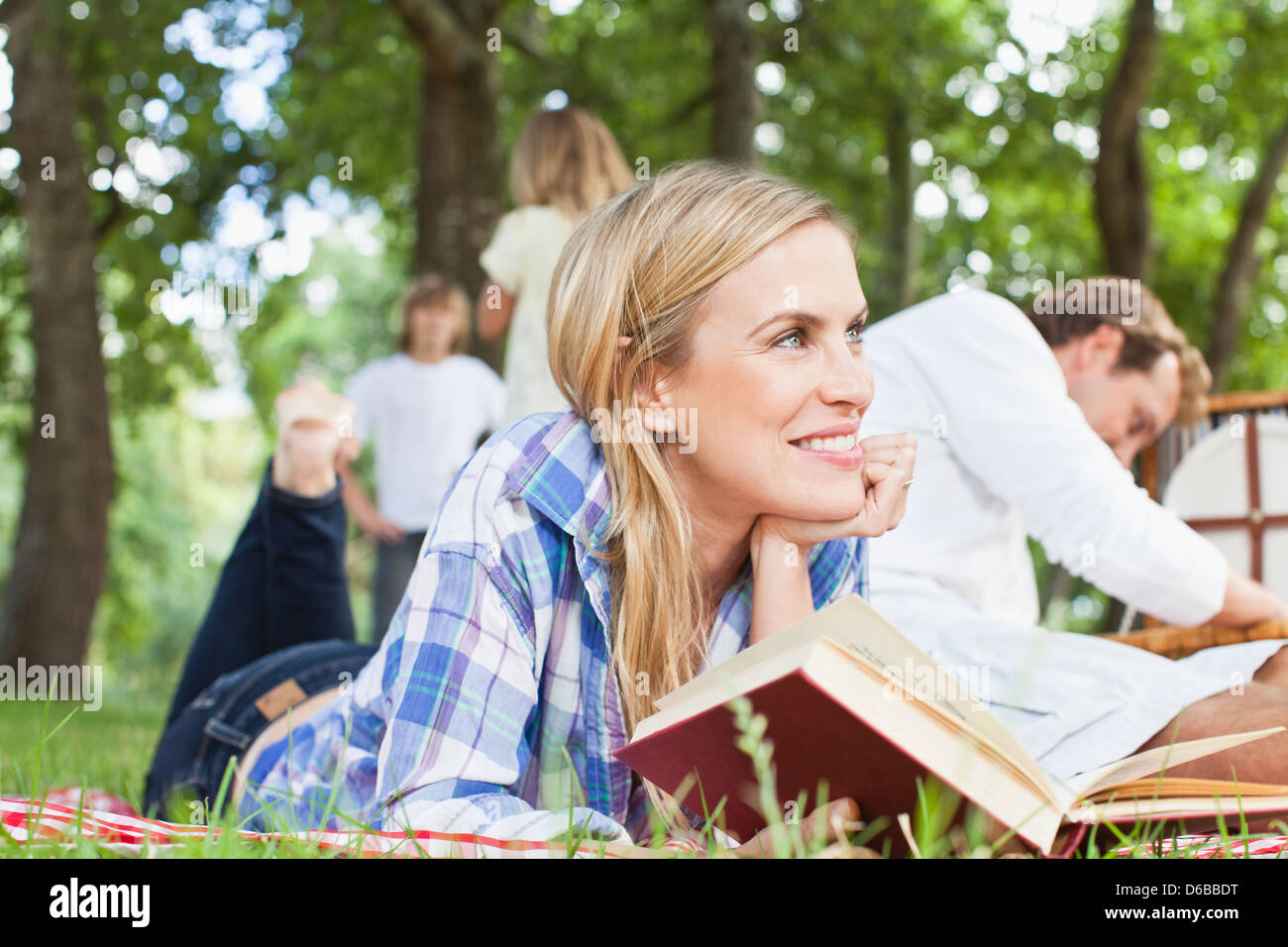 Woman reading on blanket in park Banque D'Images