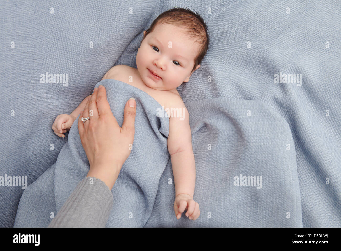 Mère tapotant baby boy in bed Banque D'Images