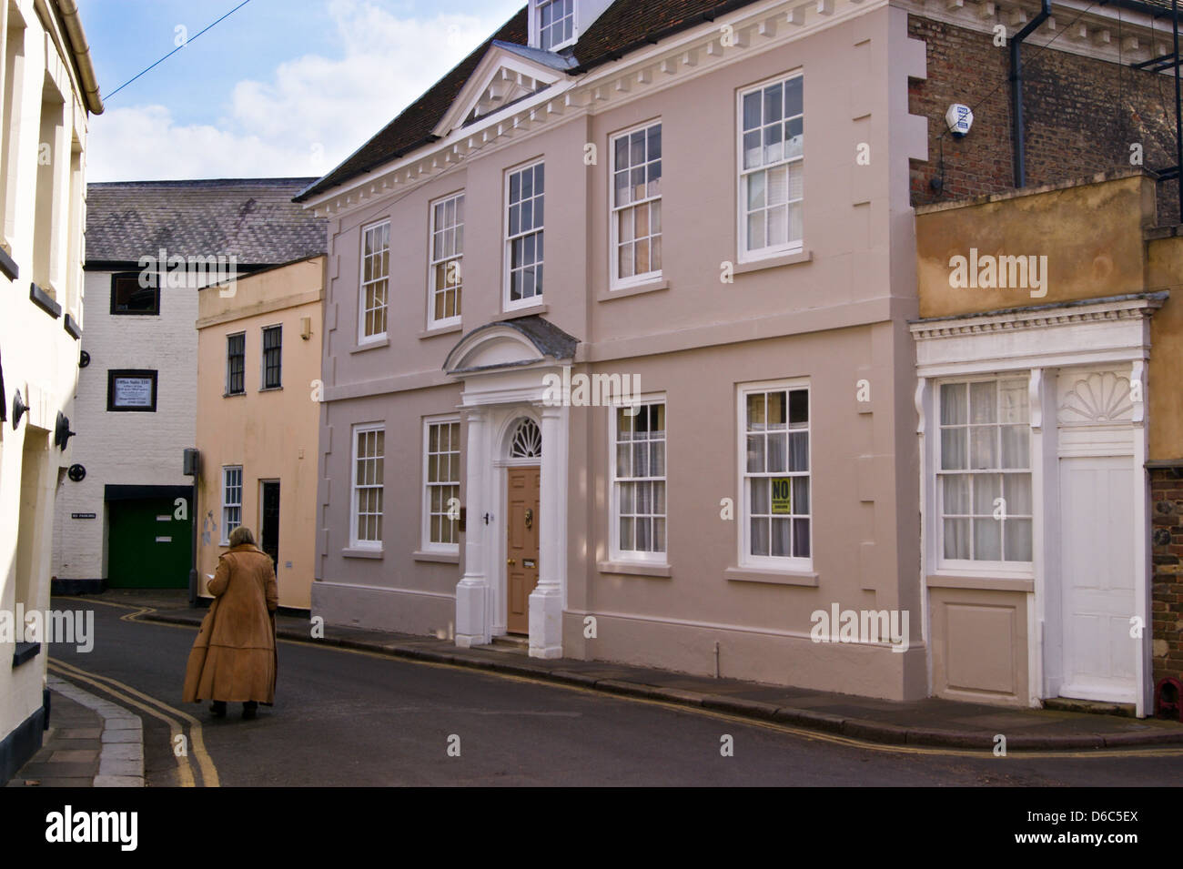 Une femme dans un manteau de fourrure longue balade passé Oxley House, Manoir géorgien, n°19 Nelson Street, King's Lynn, Norfolk, Angleterre Banque D'Images