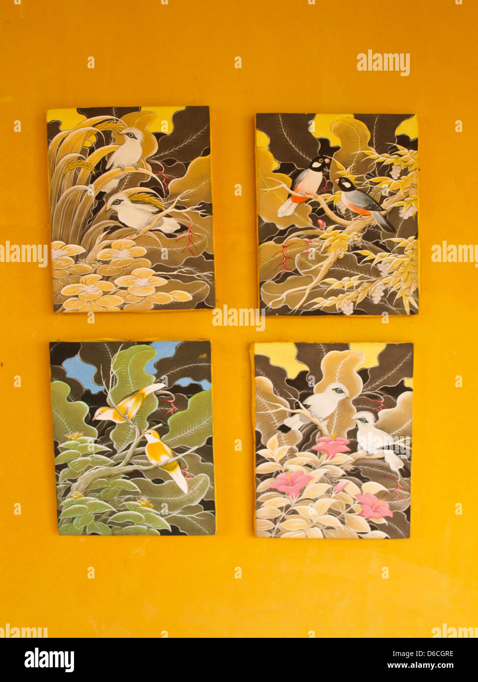 Quatre cadres de la peinture d'oiseaux sur mur jaune Banque D'Images