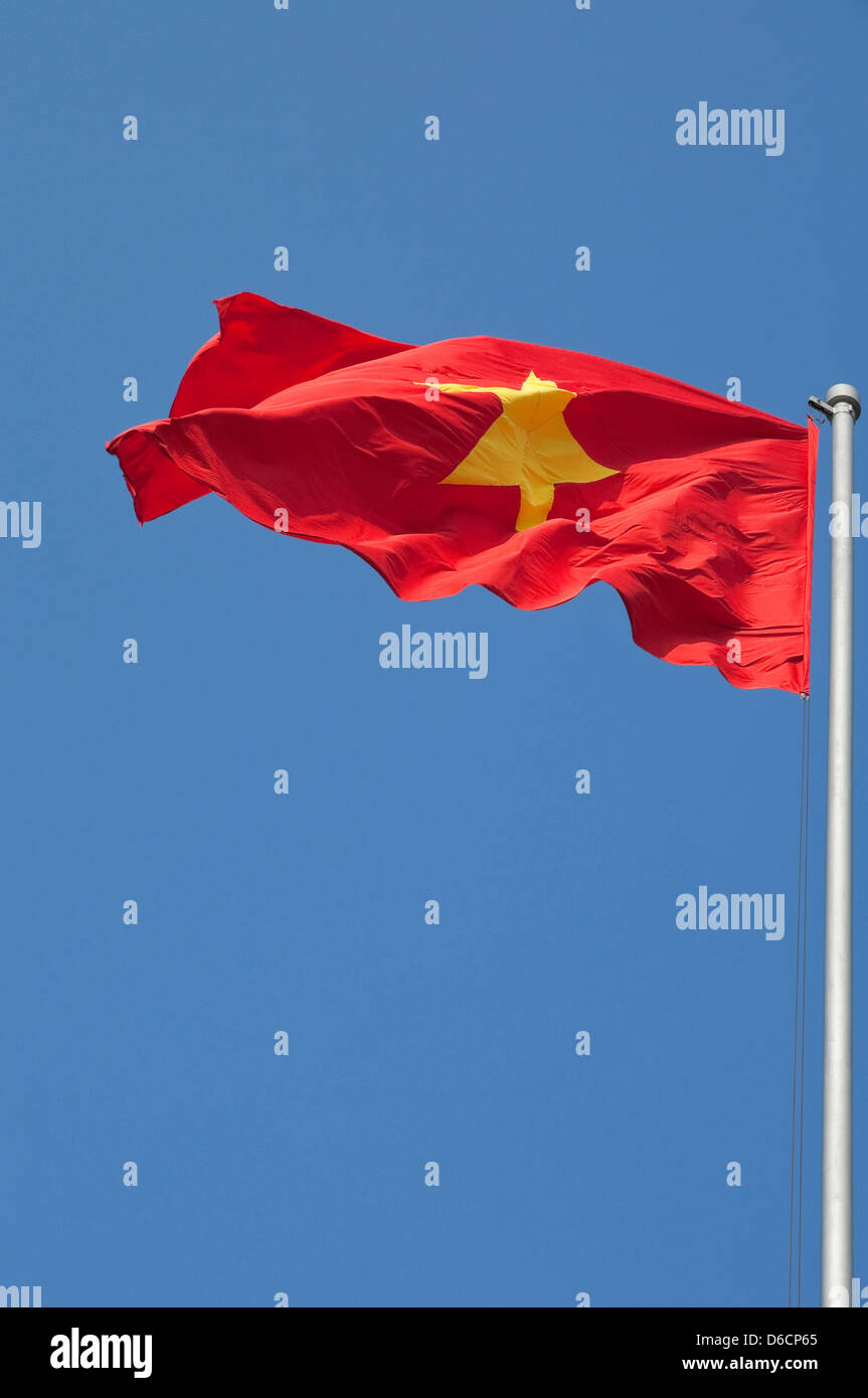 Vue verticale du drapeau national du Vietnam [cờ đỏ sao vàng] drapeau rouge avec étoile jaune fullmast contre un ciel bleu. Banque D'Images