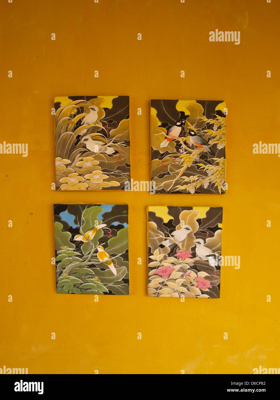 Quatre cadres de la peinture d'oiseaux sur mur jaune Banque D'Images