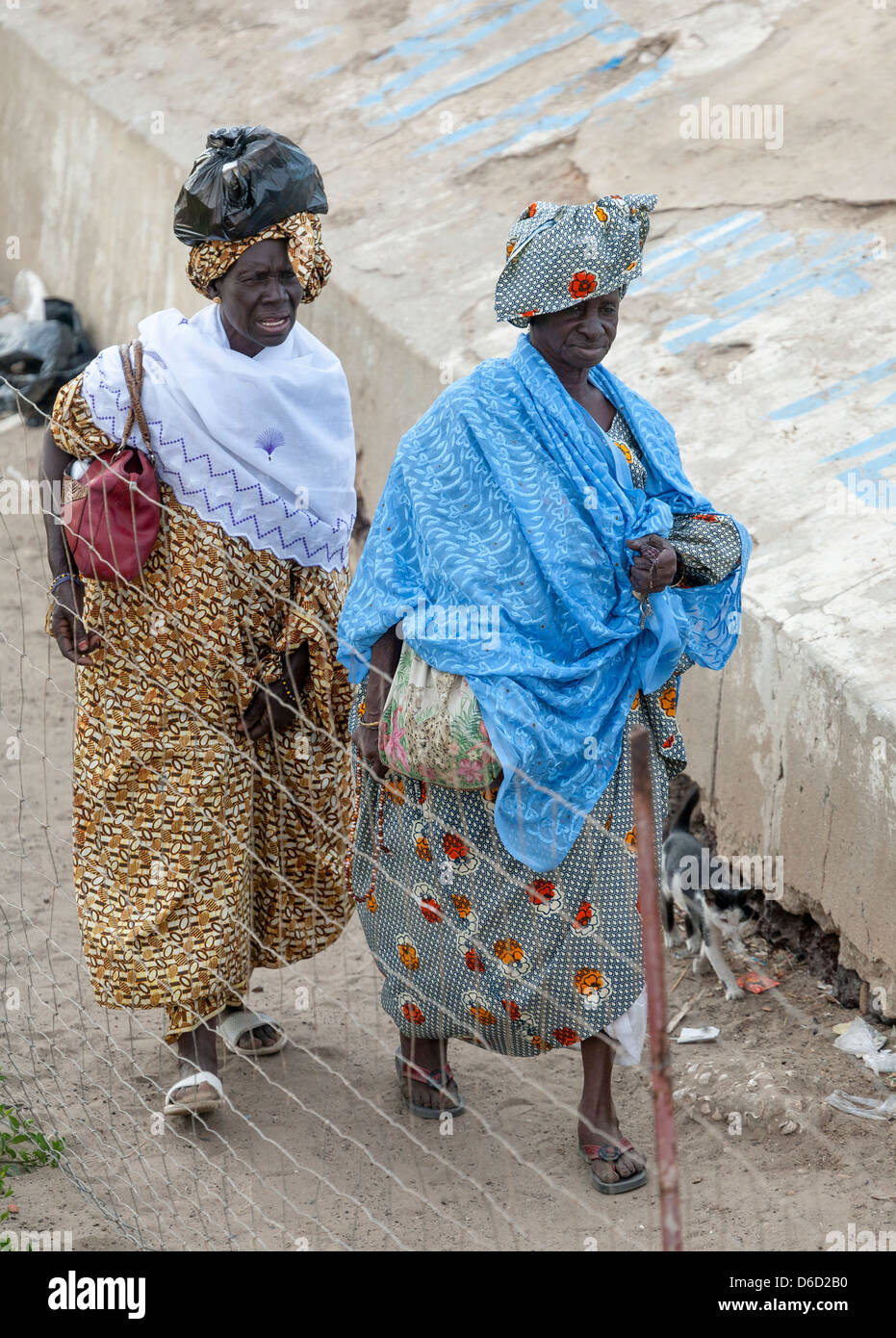 Deux personnes âgées sénégalaises en costume traditionnel et portant leur shopping à pied Banque D'Images