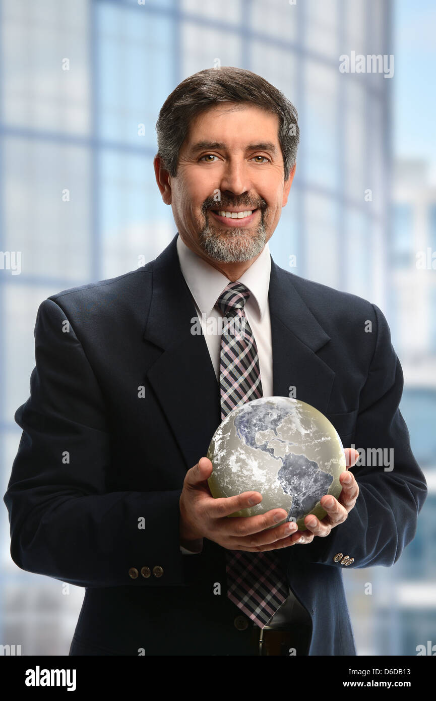 Portrait of Hispanic businessman holding earth in office building Banque D'Images