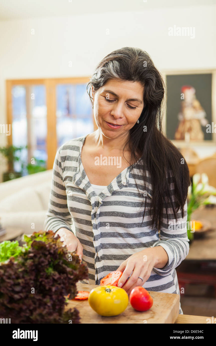 Plus Hispanic woman chopping fruit en cuisine Banque D'Images