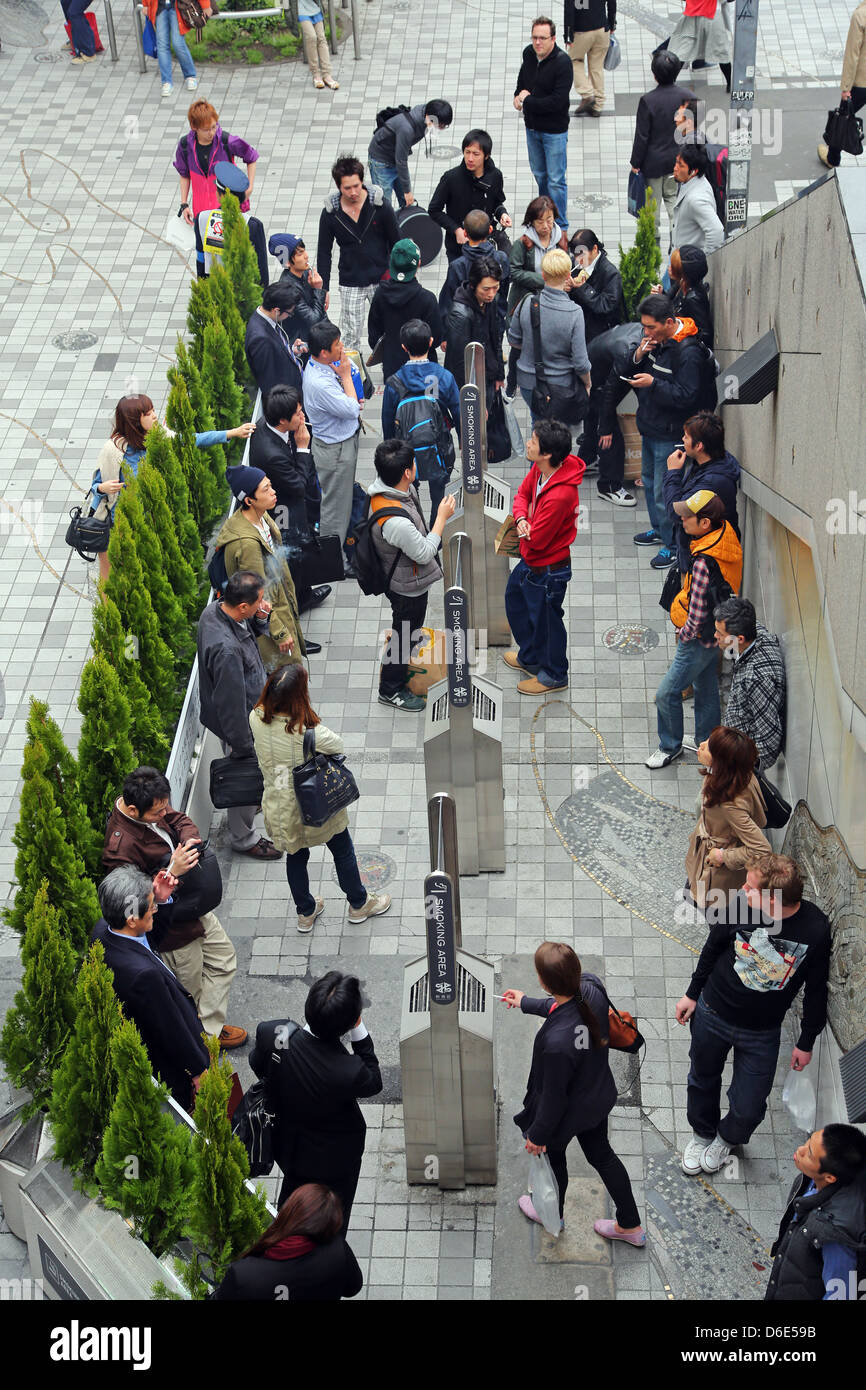 Zone fumeurs à l'extérieur avec les gens qui fument des cigarettes dans la rue à Shinjuku, Tokyo, Japon Banque D'Images
