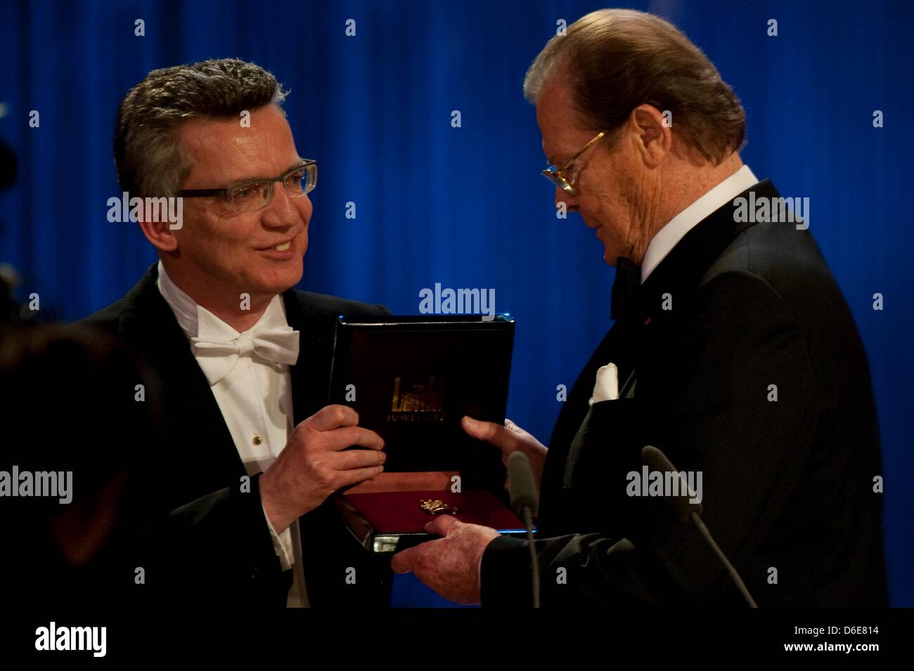 Le ministre allemand de la Défense Thomas de Maiziére (CDU)(L) mains l'acteur Britannique Roger Moore la médaille St-Georgs à la 7e SemperOpernball Smperoper à l'opéra de Dresde, Allemagne. Plus de 2200 invités ont été invités à l'événement. Photo : Sebastian Kahnert Banque D'Images