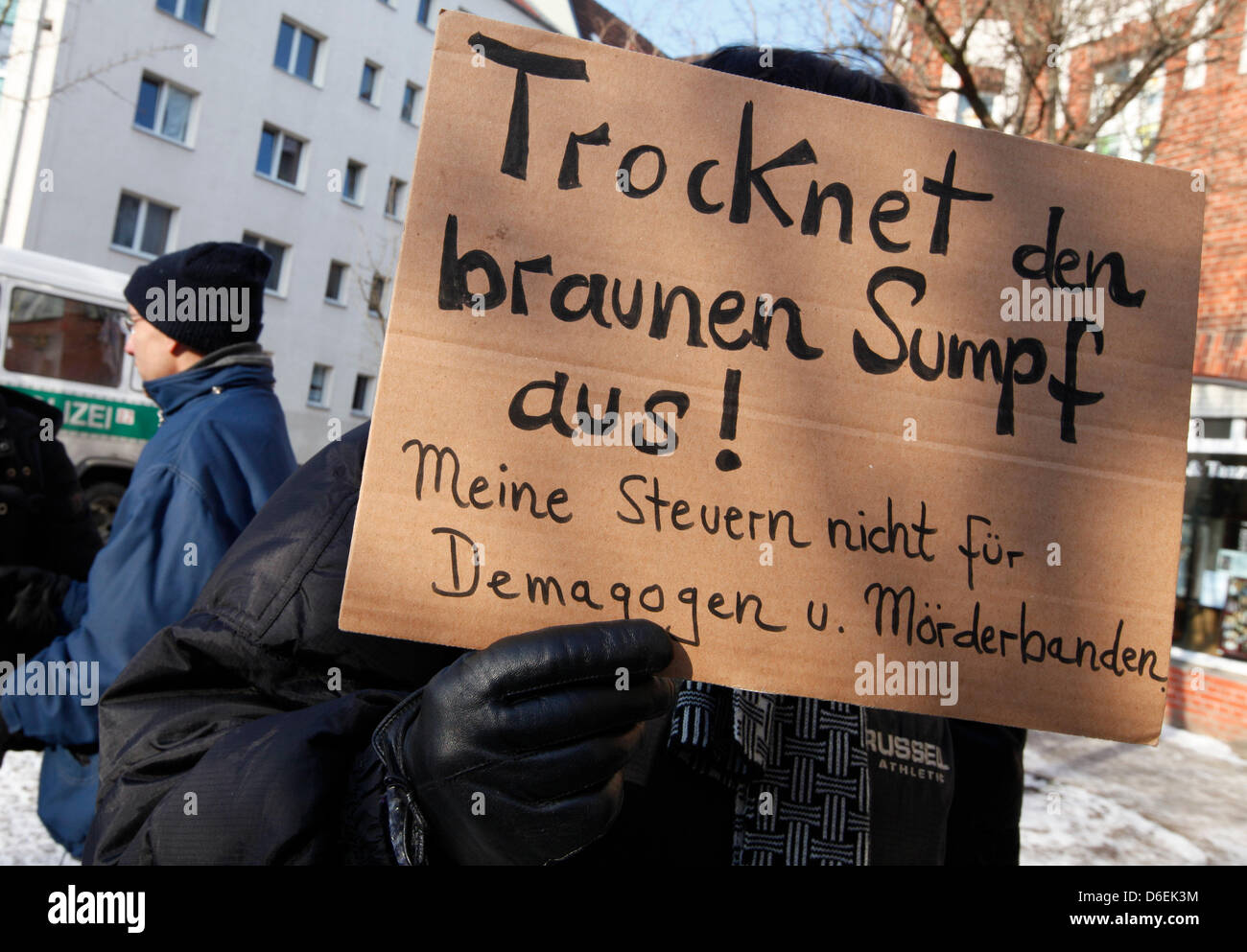 Un manifestant tient une bannière disant "Trocknet den braunen Sumpf aus ! Meine nicht für Steuern und Demagogen Moerderbanden' ('Dry le marais brun ! Pas d'impôts pour les démagogues et les meurtriers') au cours d'une manifestation contre le parti d'extrême droite NPD in front of the NPD siège à Berlin, Allemagne, 04 février 2012. Photo : FLORIAN SCHUH Banque D'Images