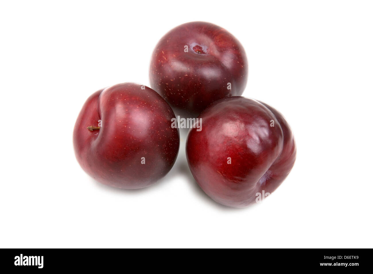 Prunes rouges sur fond blanc Banque D'Images