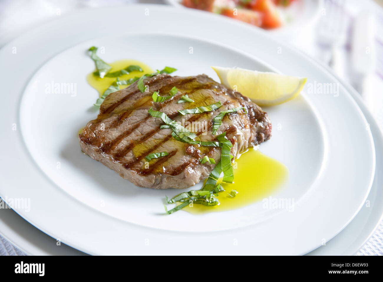 Bifteck de faux-filet Griddled servi avec de l'huile d'olive infusée à l'ail et le basilic haché. Banque D'Images