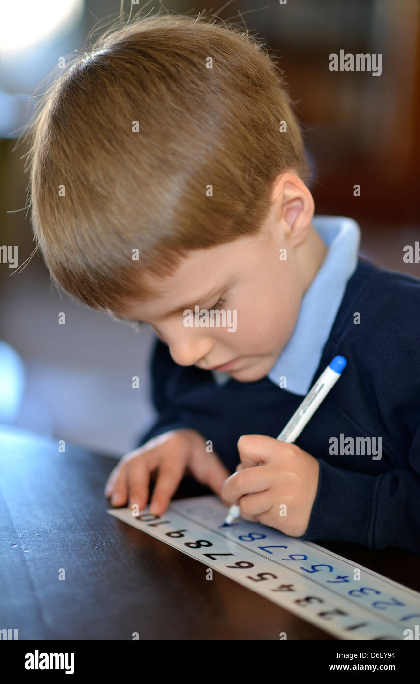 Un écolier de 5 ans apprendre à écrire les nombres. Banque D'Images