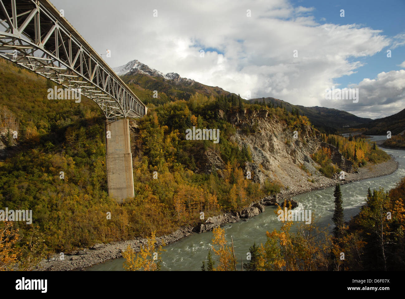 Montagnes couvertes de neige sont à l'arrière-plan comme une rivière coule sous un pont dans l'Alaska. Banque D'Images